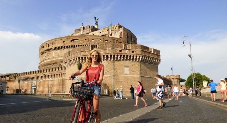 A Woman Traveller Posing With A Bicycle In A Beautiful Place